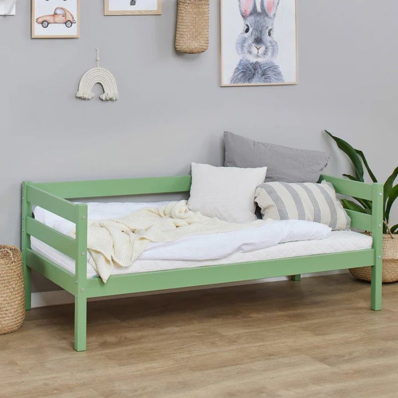 pale green wooden frame junior bed in decorated room, angled view