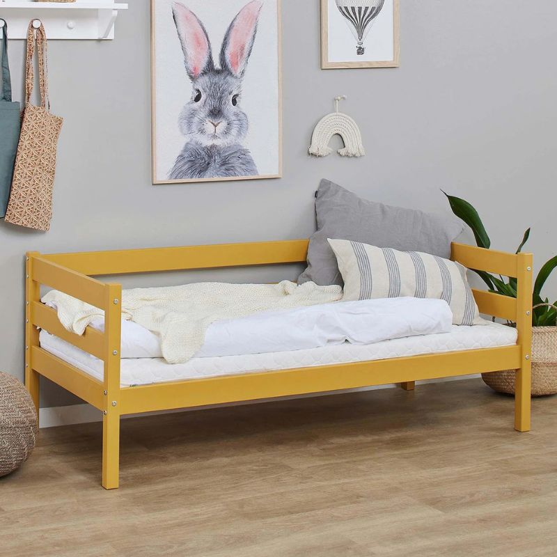 Autumn yellow wooden frame junior bed in decorated room, angled view