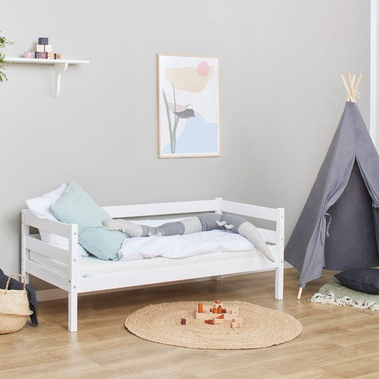 white wooden frame junior bed in  decorated room, angled view