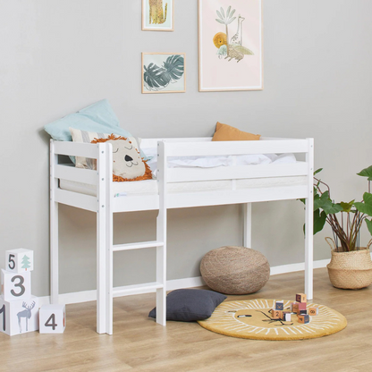 White children's bed with toys and cushions in a room with framed pictures on the wall.